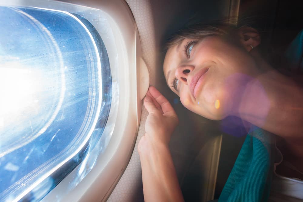 Preparing for a holiday with a medical condition: Young woman looking out plane window