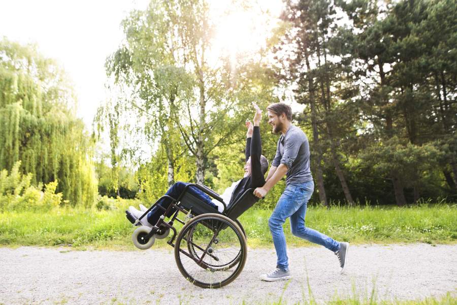 Son pushing father in a wheelchair who is Travelling With A Disability